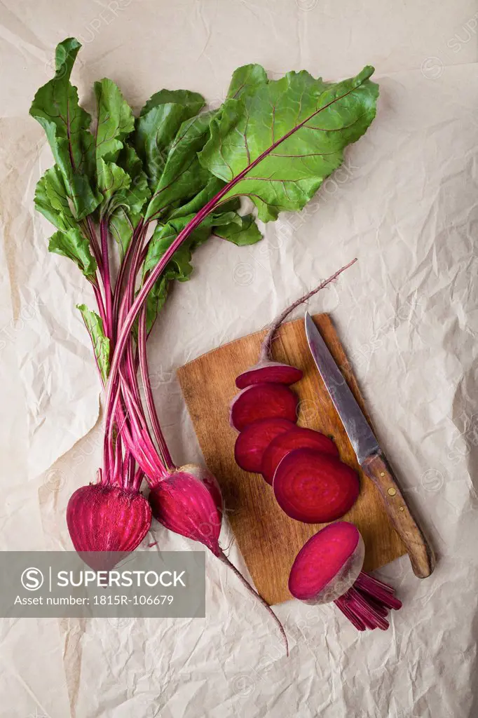 Sliced beetroots with knife and chopping board on parchment paper