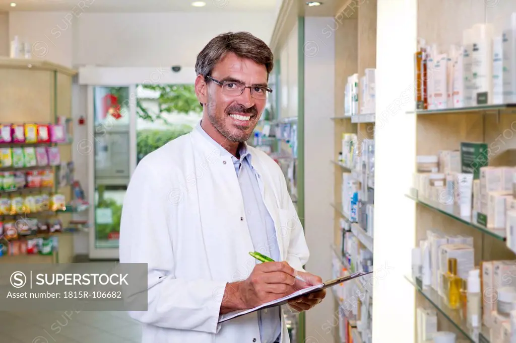 Germany, Brandenburg, Pharmacist checking products, smiling, portrait