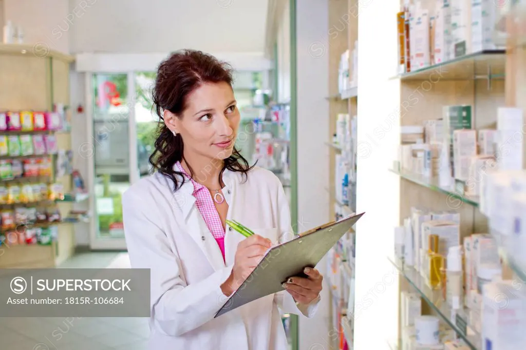 Germany, Brandenburg, Pharmacist checking products in pharmacy