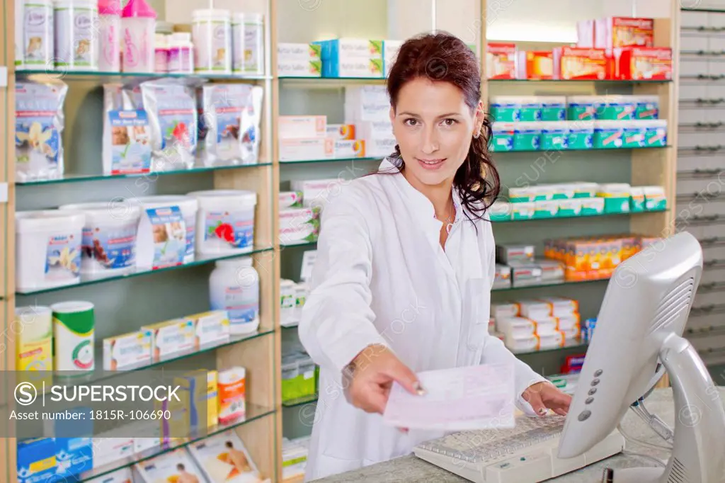 Germany, Brandenburg, Pharmacist holding prescription, smiling, portrait