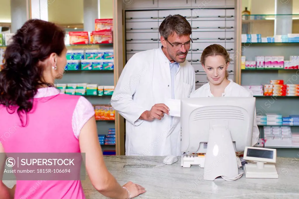 Germany, Branderburg, Pharmacist using computer, woman standing in foreground