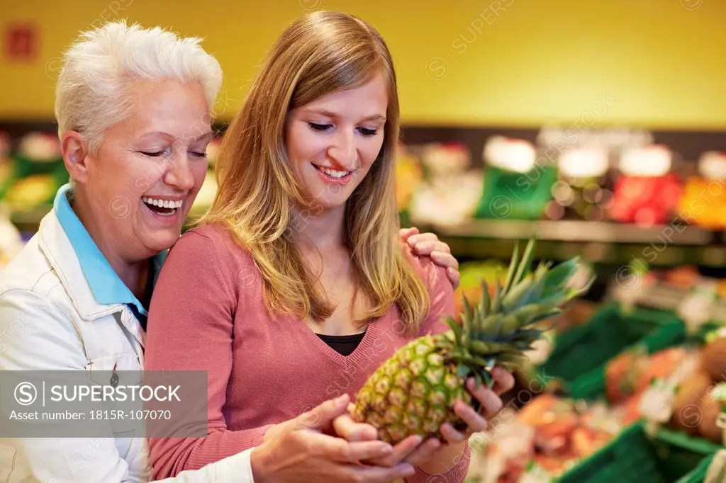 Germany, Cologne, Women with pineapple in supermarket