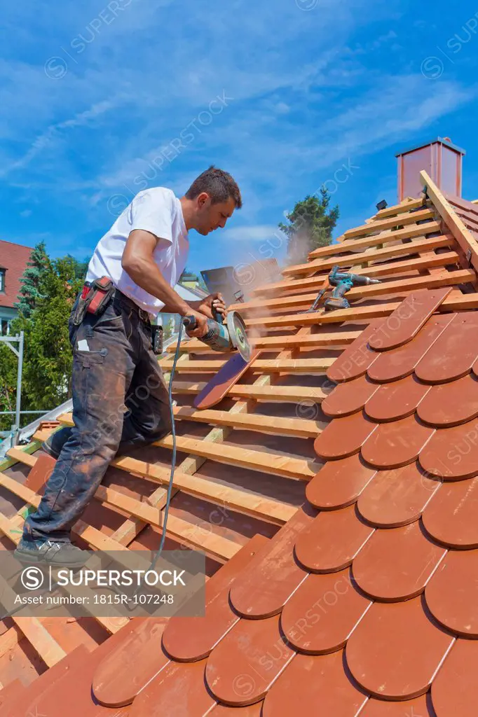 Germany, Baden_Wuerttemberg, Stuttgart, Mid adult man cutting roof tile