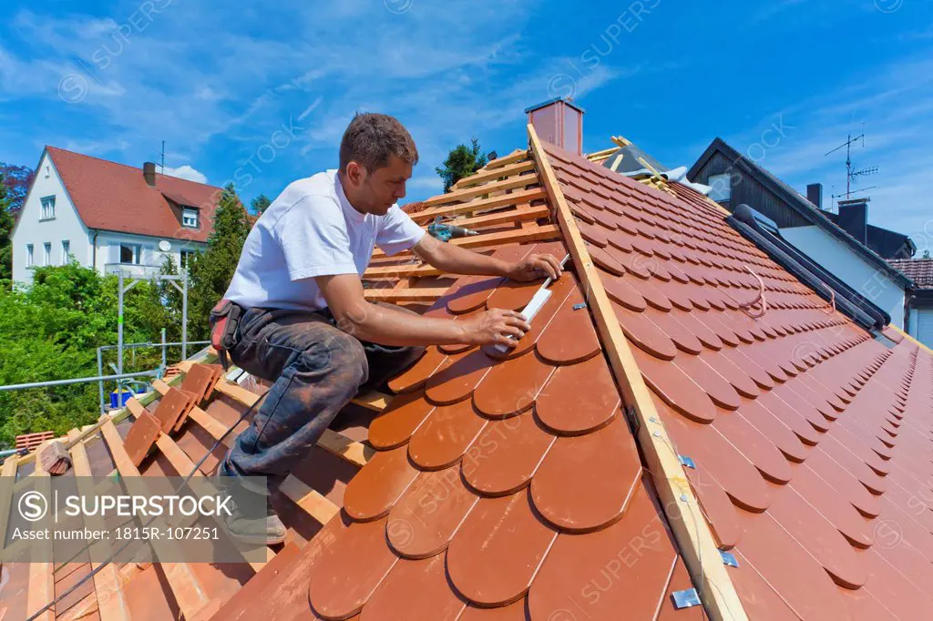 Germany, Baden_Wuerttemberg, Stuttgart, Mid adult man measuring roof tile