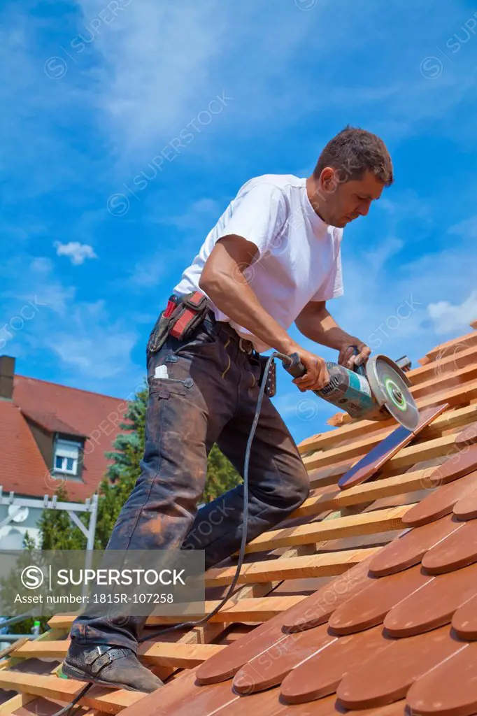 Germany, Baden_Wuerttemberg, Stuttgart, Mid adult man cutting roof tile