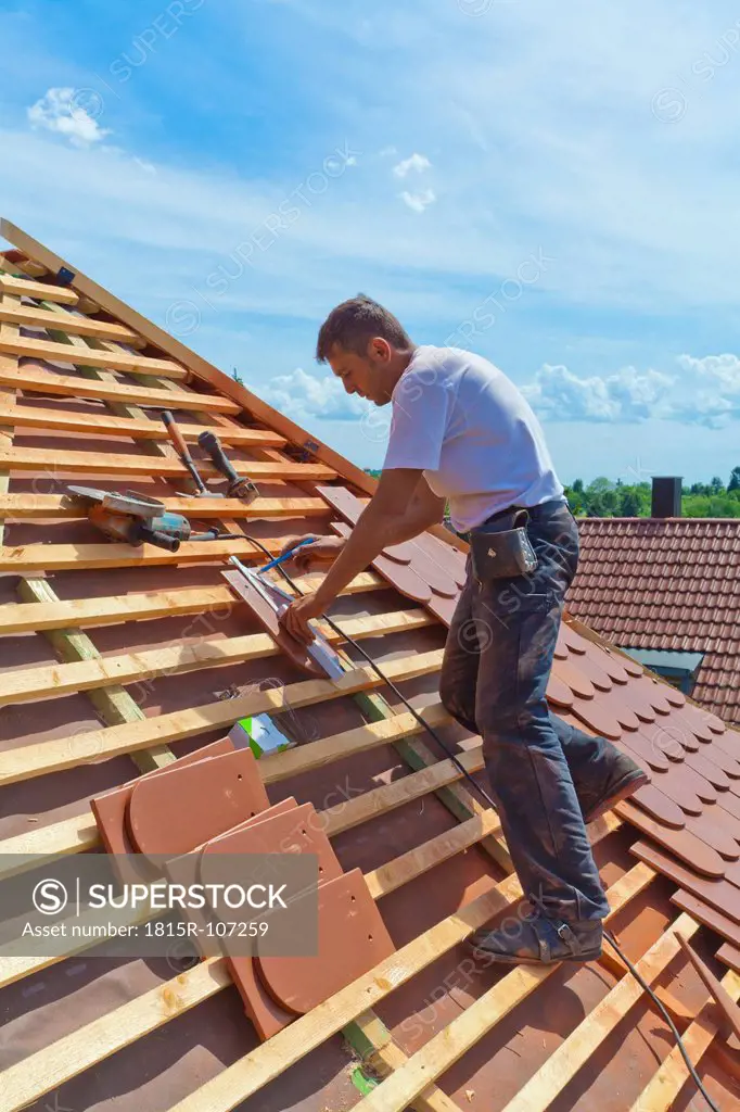 Germany, Baden_Wuerttemberg, Stuttgart, Mid adult man measuring roof tile