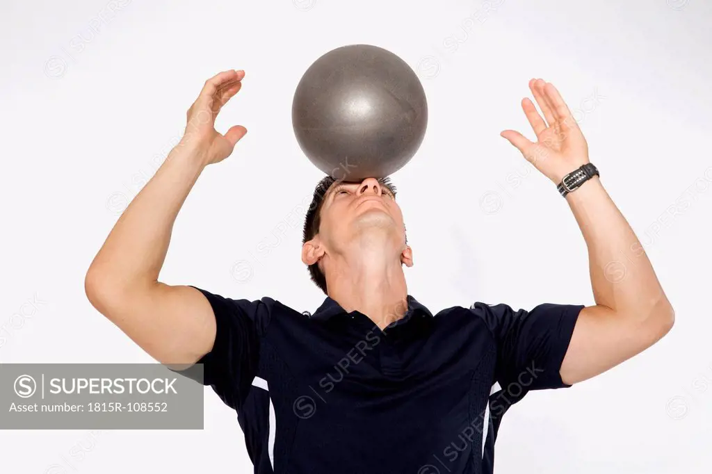Personal trainer balancing ball on forehead, close up