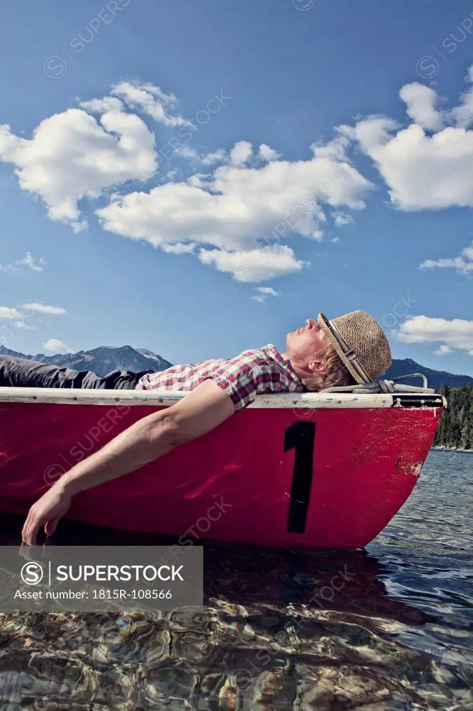Germany, Bavaria, Mid adult man sleeping in rowing boat
