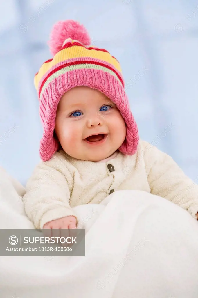 Baby girl in woolly hat, smiling, close up