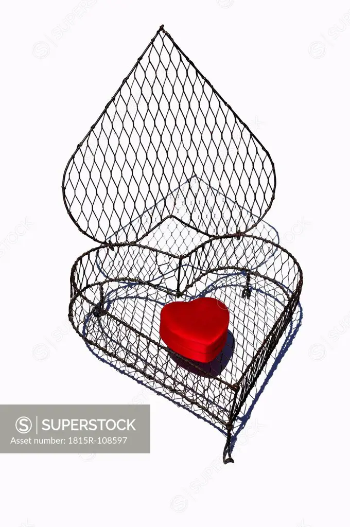 Heart shape cage made by wire with red heart on white background, close up
