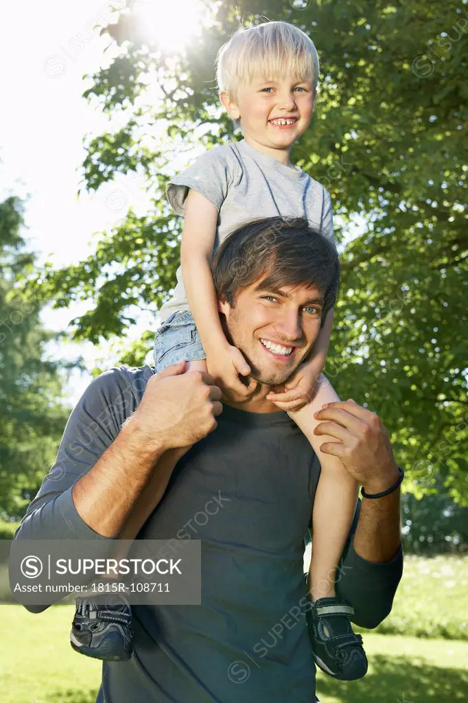 Germany, Cologne, Father carrying son on shoulders, smiling, portrait