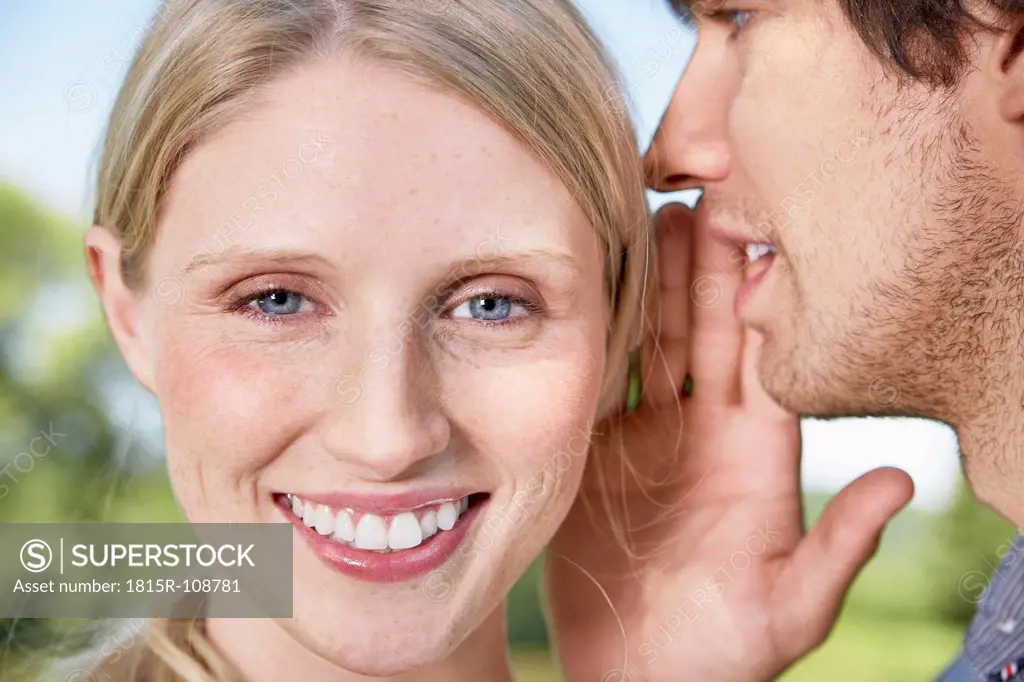 Germany, Cologne, Young man whispering to woman
