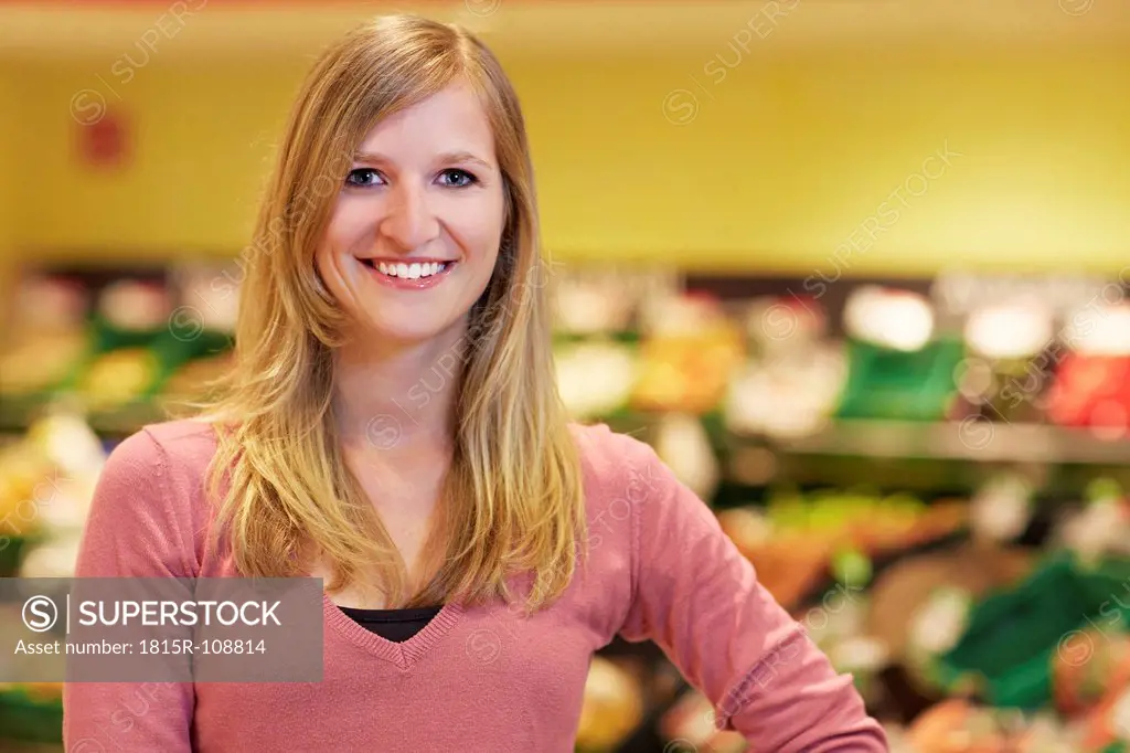 Germany, Cologne, Young woman in supermarket, smiling, portrait