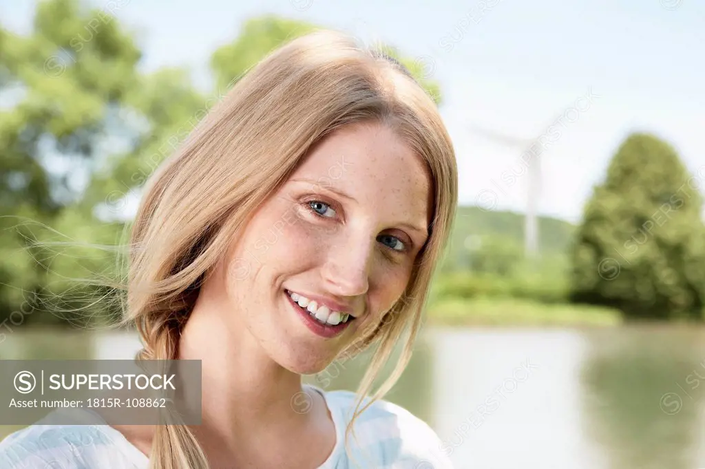 Germany, Cologne, Young woman smiling, portrait, wind turbine in background