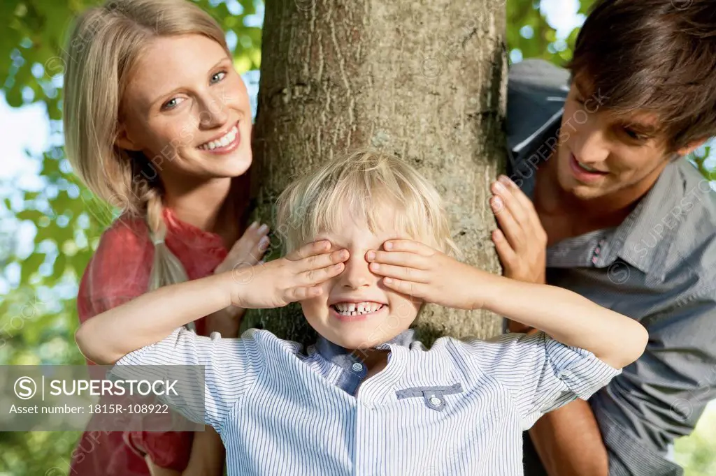 Germany, Cologne, Boy playing hide and seek with parents