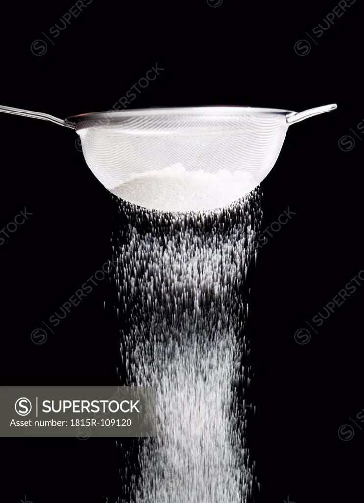 White flour in sieve against black background