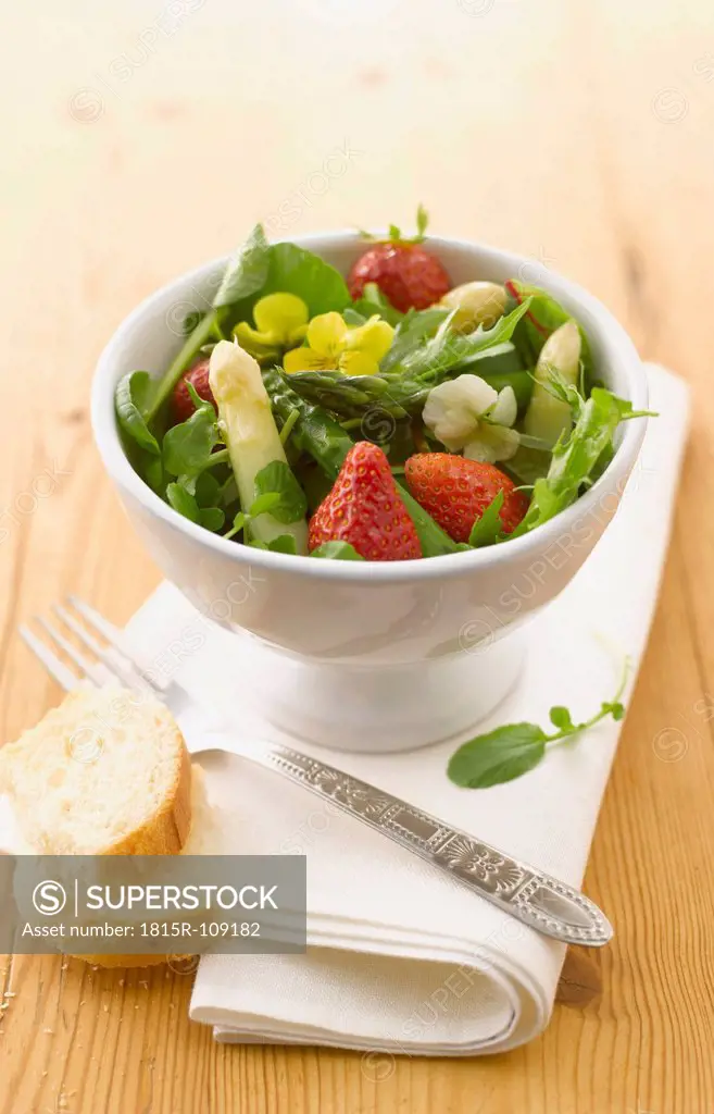 Bowl of wild herbs salad with asparagus and strawberries
