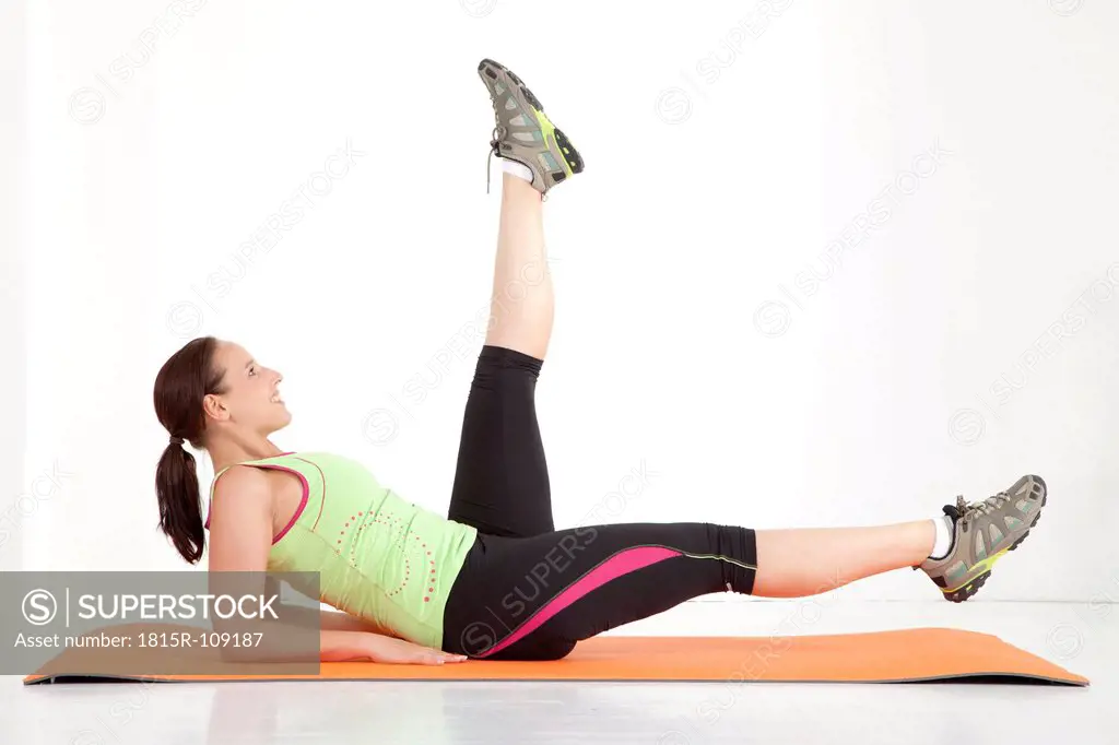 Young woman stretching leg on exercise mat