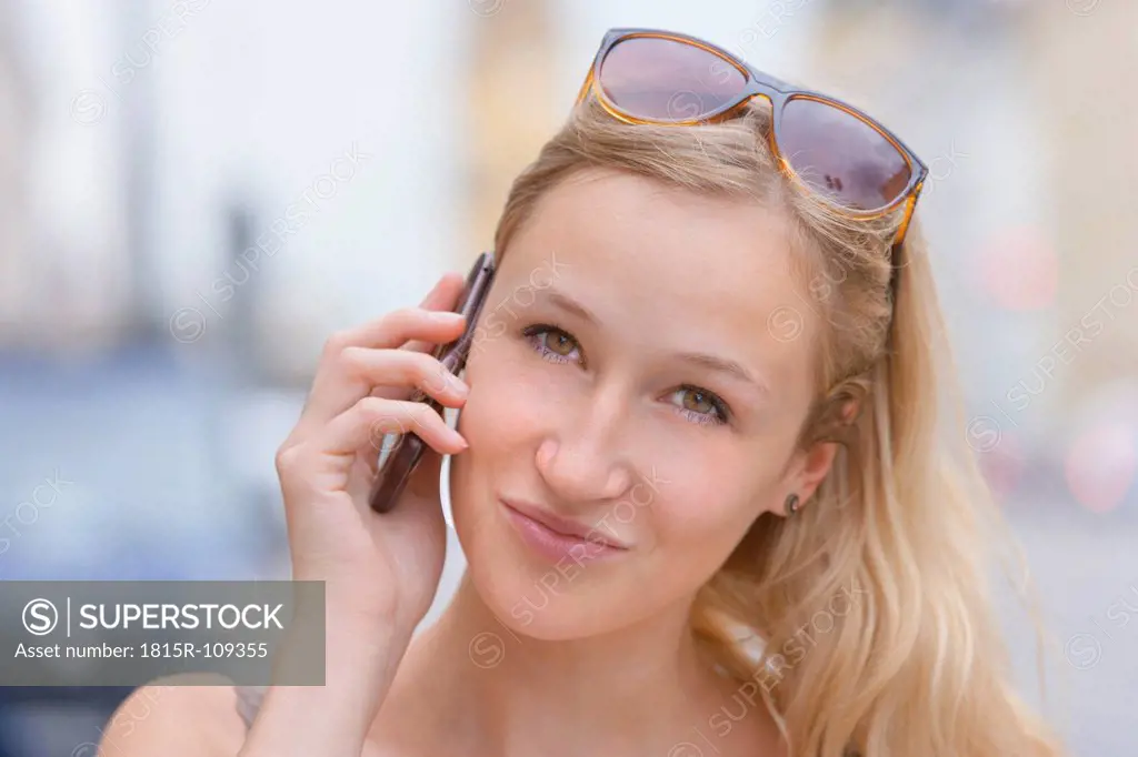 Germany, Bavaria, Munich, Young woman talking on phone in front of Bavarian State Library at Ludwigstrasse