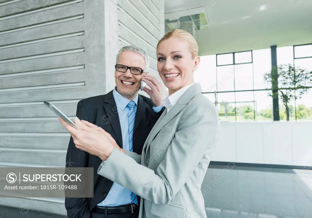 Germany, Stuttgart, Businesswoman with digital tablet while man talking on phone