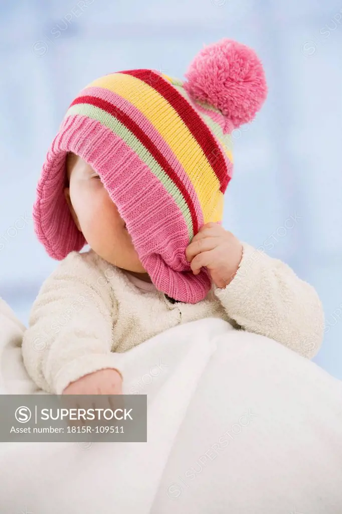 Baby girl covering face with hat, close up