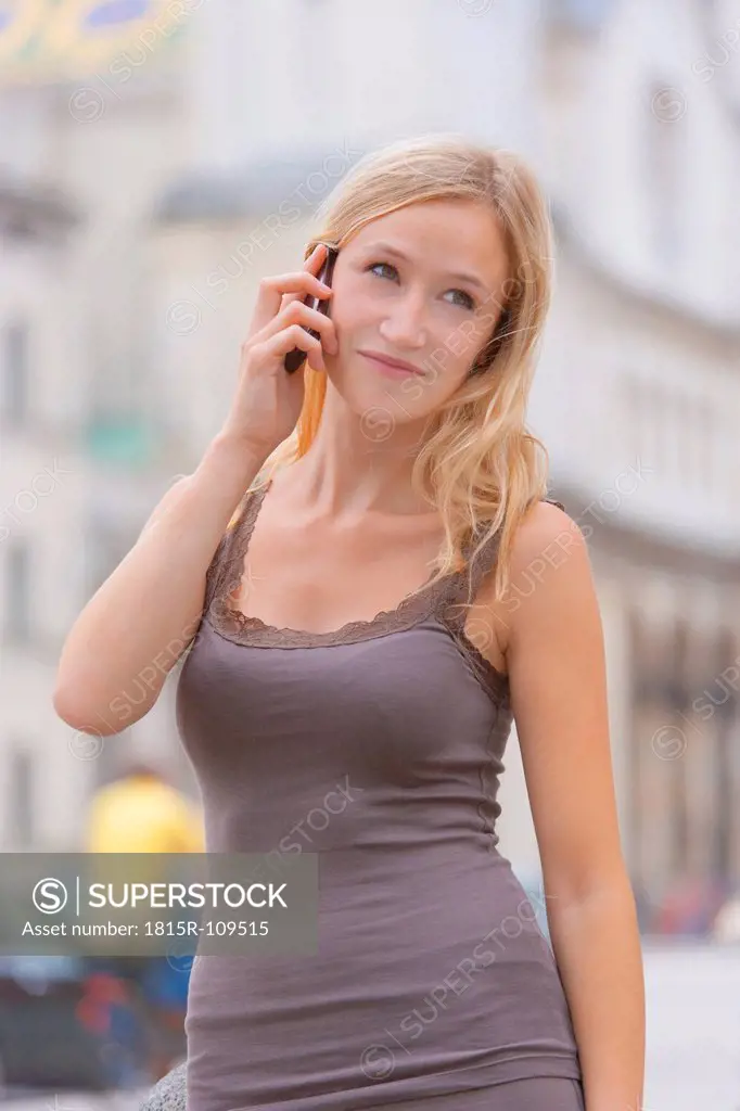 Germany, Bavaria, Munich, Young woman talking on phone in front of Ludwig Maximilian University