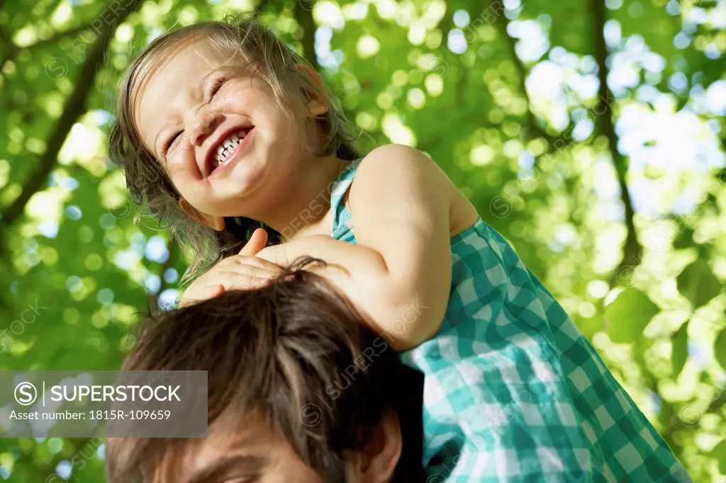 Germany, Cologne, Father carrying daughter on shoulders, smiling