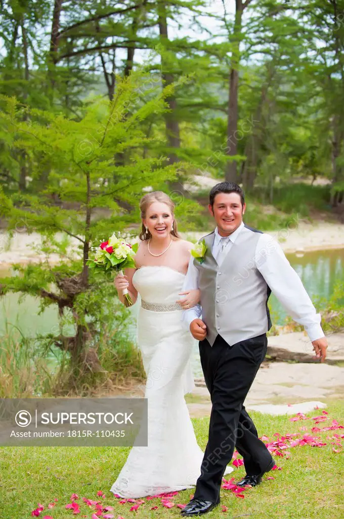 USA, Texas, Bride and groom walking on grass, smiling