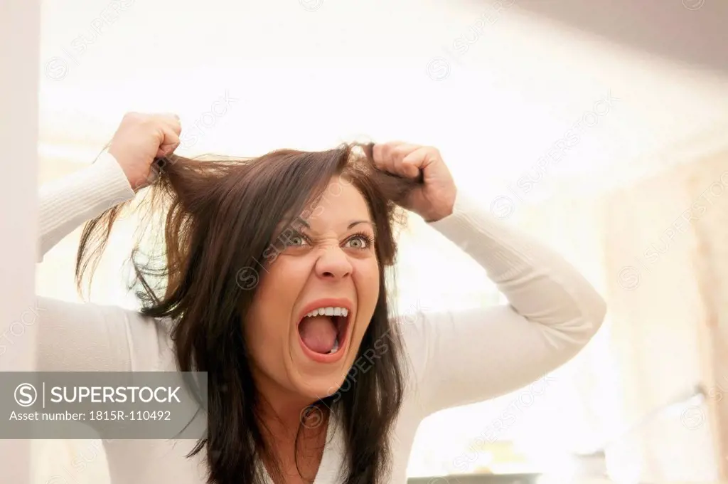 Germany, Berlin, Young woman worried about tousled hair