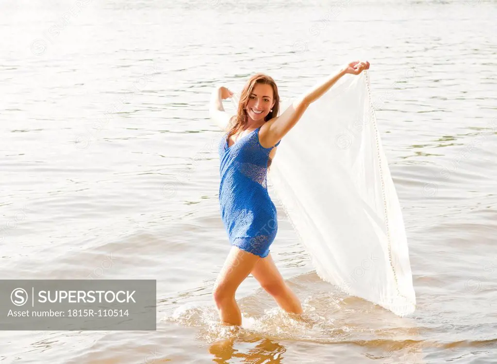 Germany, Brandenburg, Young woman holding transparent cloth on lake