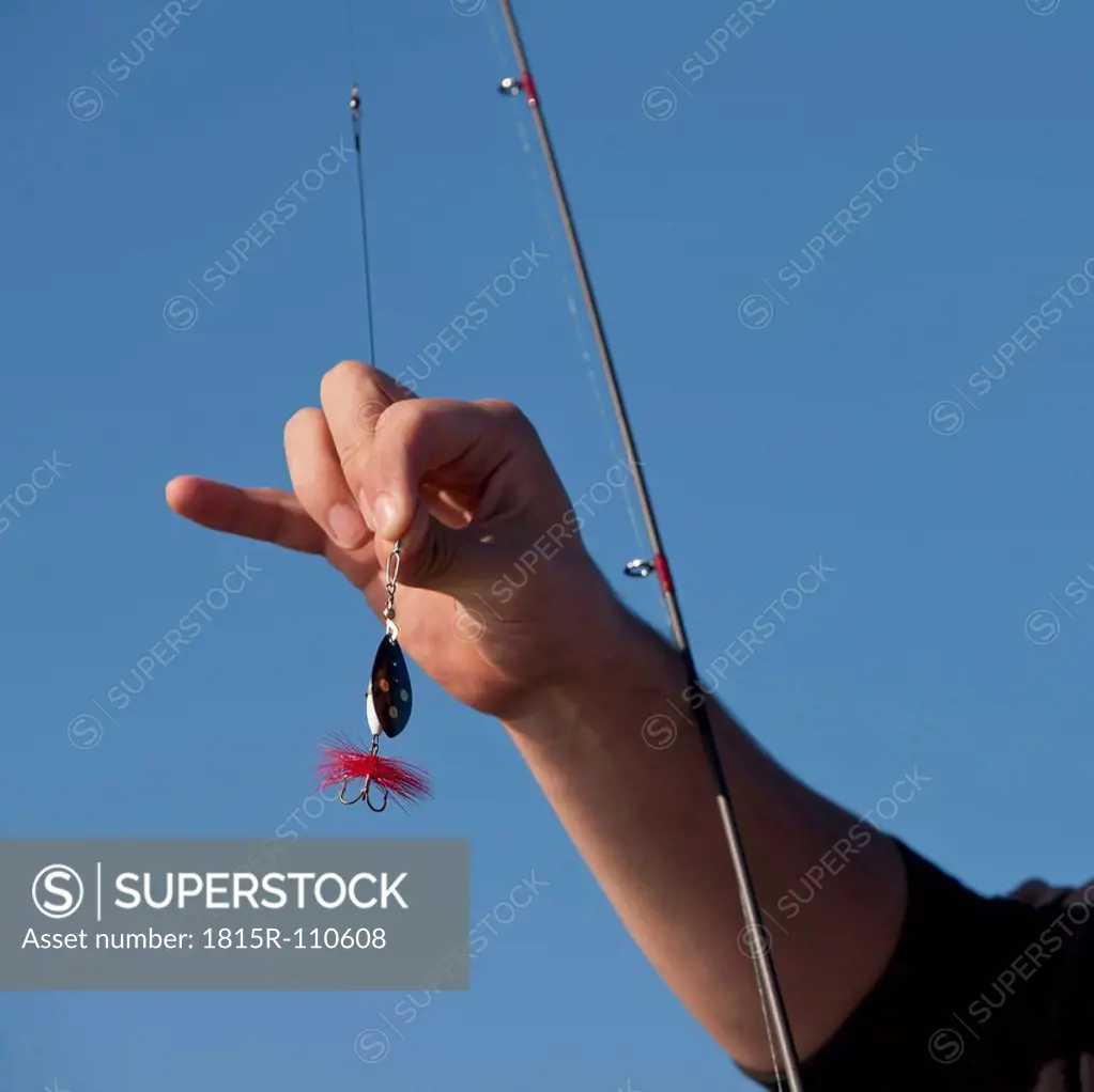 Sweden, Young man holding fishing rod with bait and hook