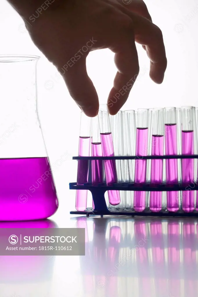 Chemist holding test tube against white background, close up