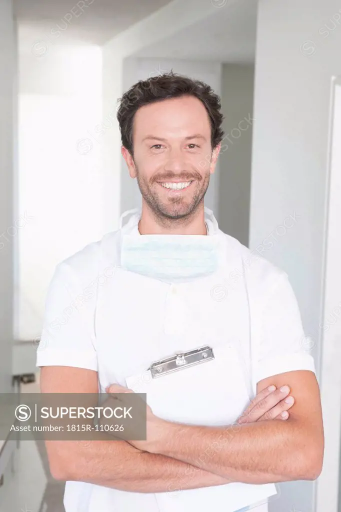 Germany, Dentist holding clip board, smiling, portrait