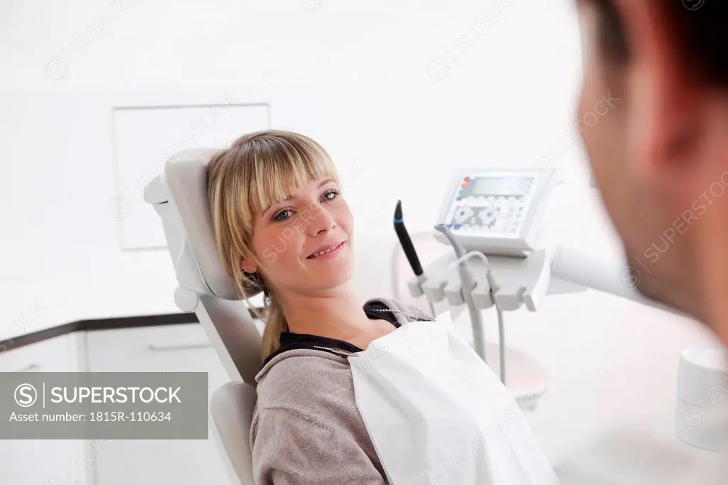Germany, Young woman in dentist chair, smiling
