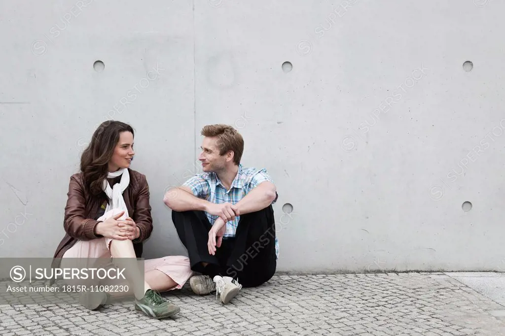 Germany, Berlin, Man and woman sitting against wall