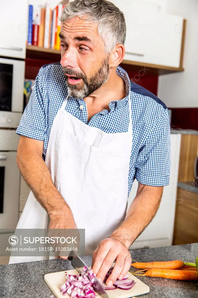 Austria, Man in kitchen chopping onions