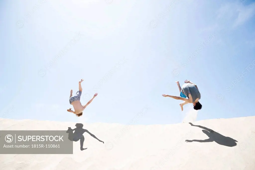 France, Two Boys jumping on sand dune
