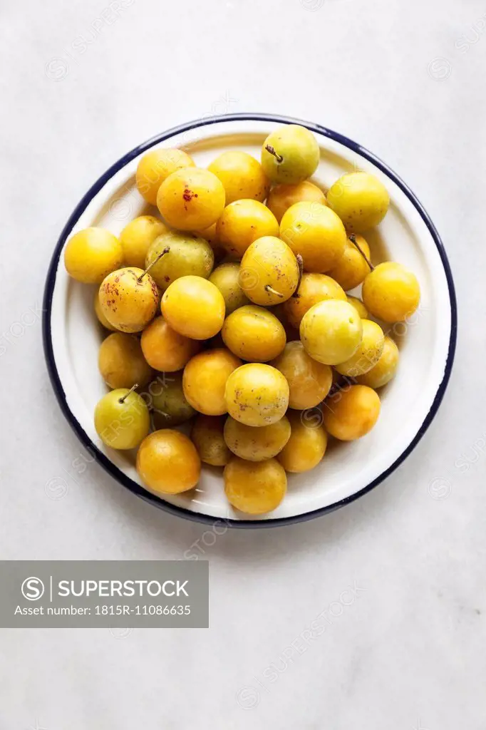 Bowl of mirabelles on white background