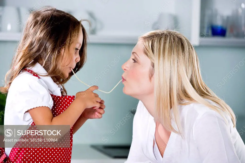 Germany, Daughter eating noodles with mother in kitchen