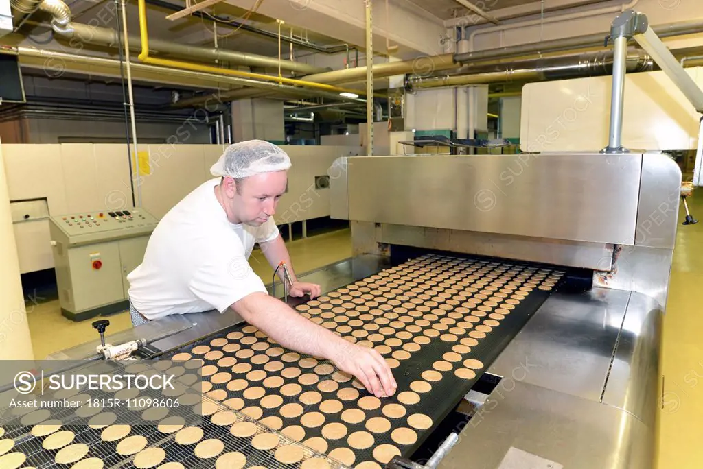 Germany, Saxony-Anhalt, man controlling cookies in a baking factory