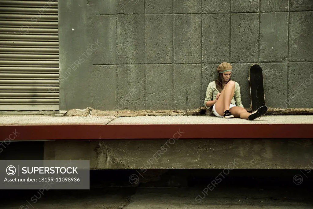 Teenage girl with skateboard at concrete wall