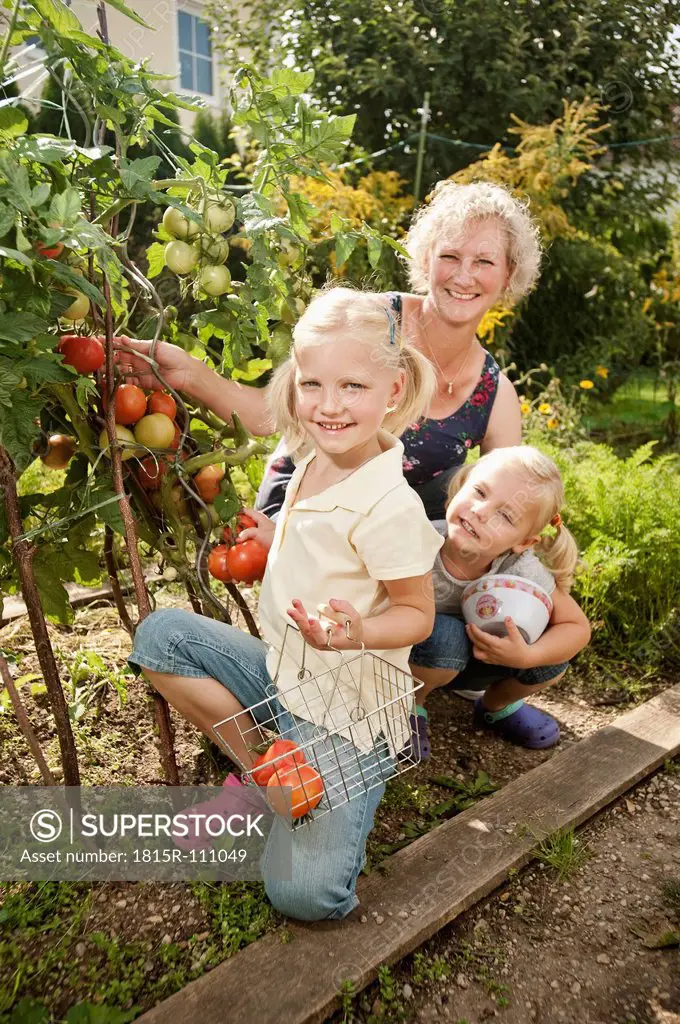 Germany, Bavaria, Grandmother with children in vegetable garden
