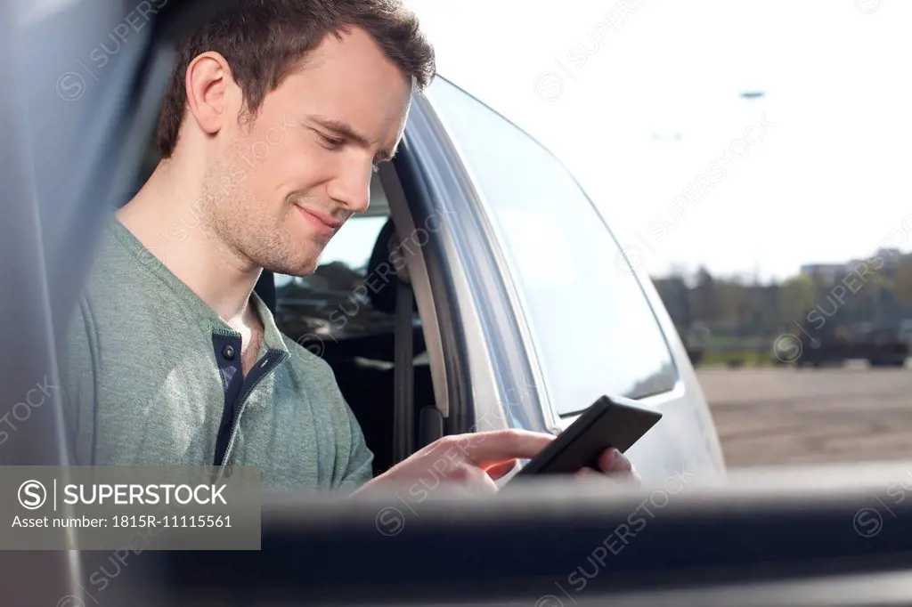 Young man using cell phone in car