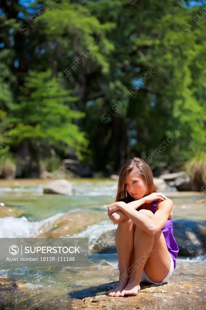 USA, Texas, Young woman sitting at Frio river