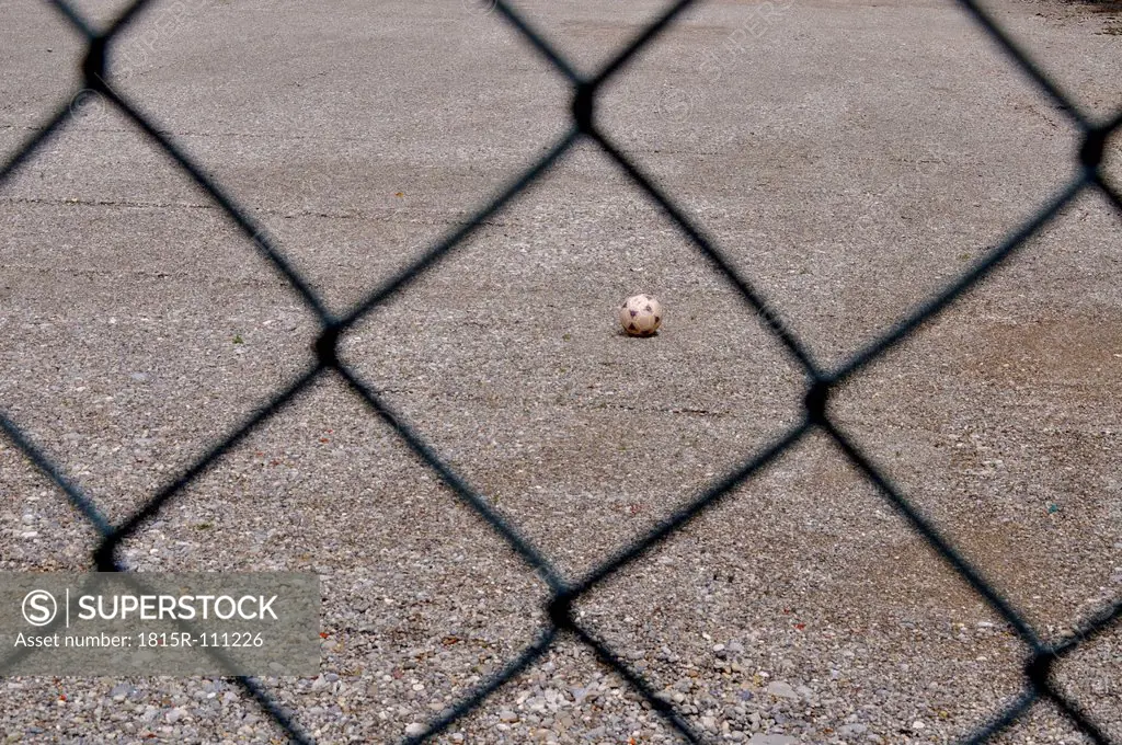 Germany, Bavaria, Football seen through wire mesh fence