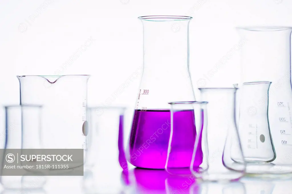 Volumetric flasks with pink solution against white background, close up