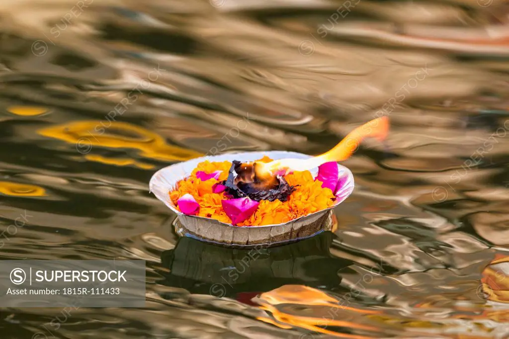 India, Uttar Pradesh,Leaf bowl with flowers and oil lamp floating on River Ganges