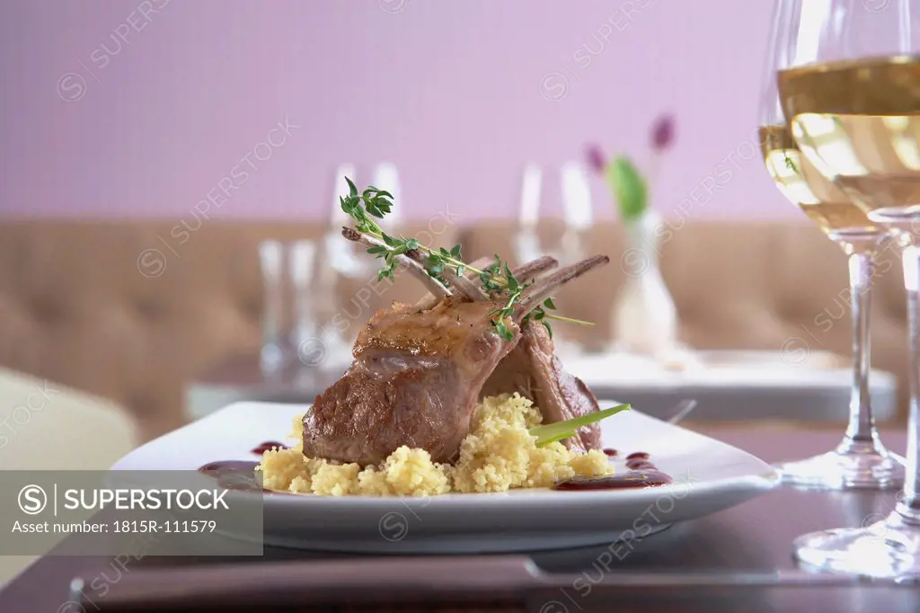 Plate of lamb loin with couscous and wine on table