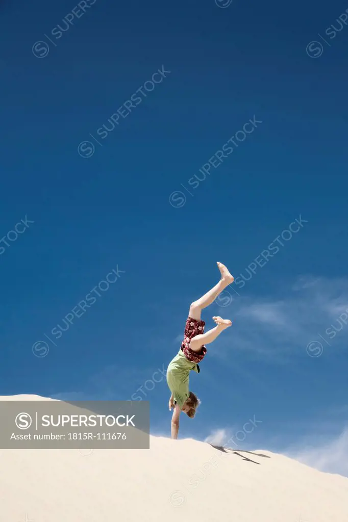 France, Boy jumping on sand dune