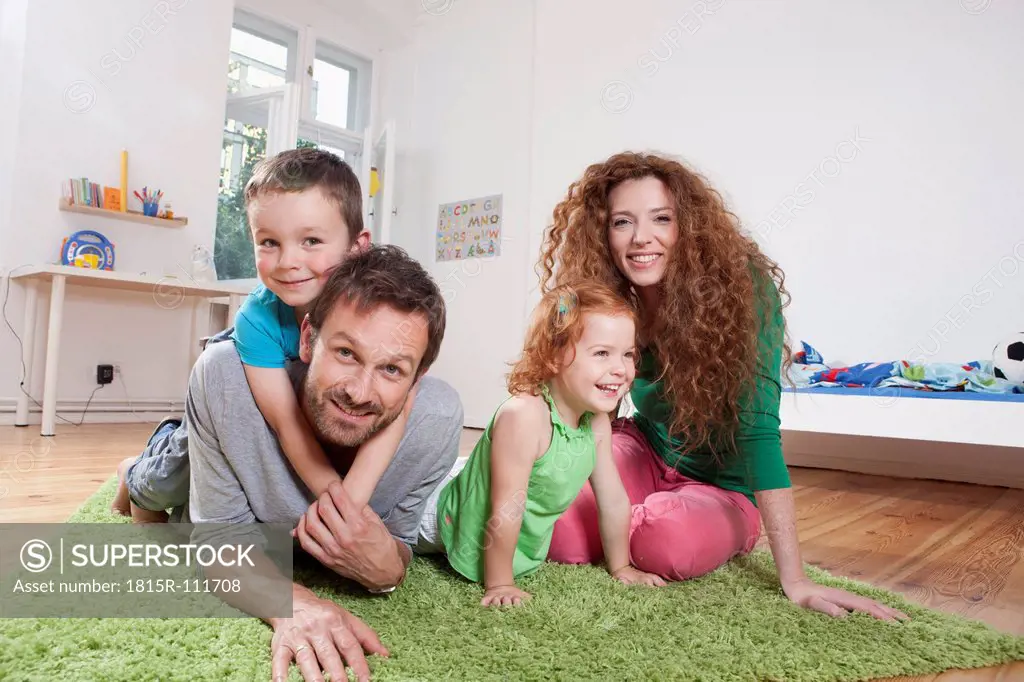 Germany, Berlin, Family sitting on floor, smiling, portrait